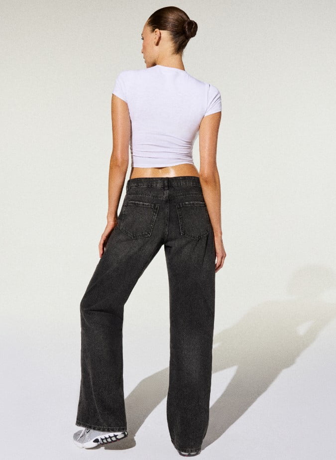 La mannequin porte un t-shirt blanc et un jean noir décontracté.