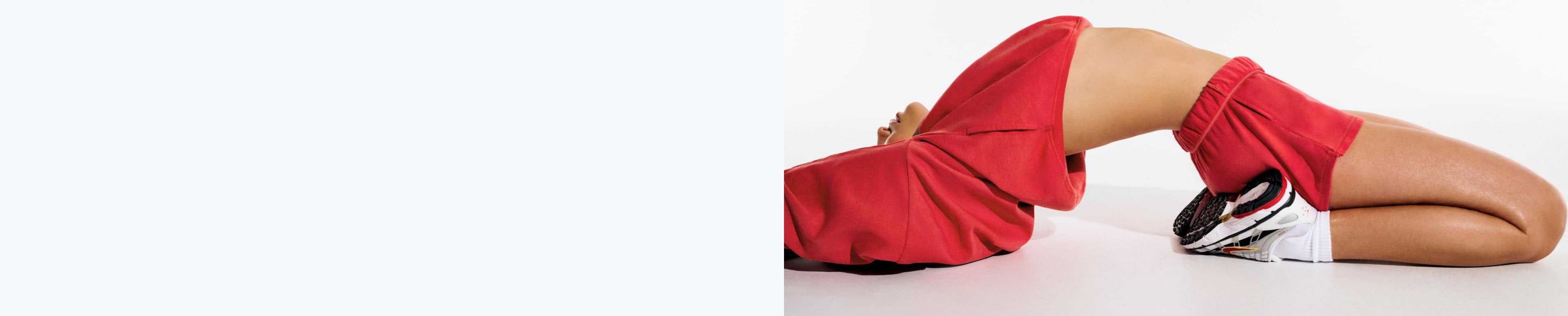 La mannequin prend la pose vêtue d'un haut à capuchon rouge et d'un short en molleton rouge.