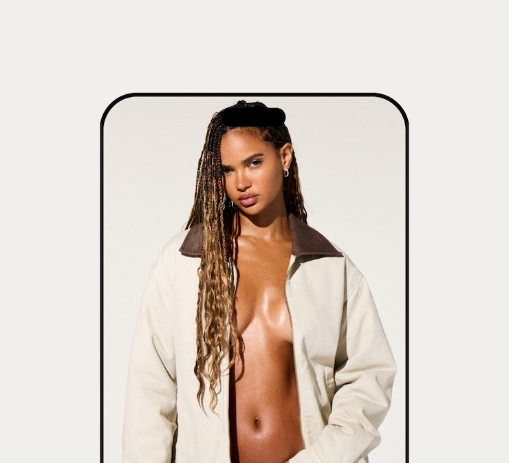 Model poses in a white worker jacket with no shirt underneath and light wash denim.