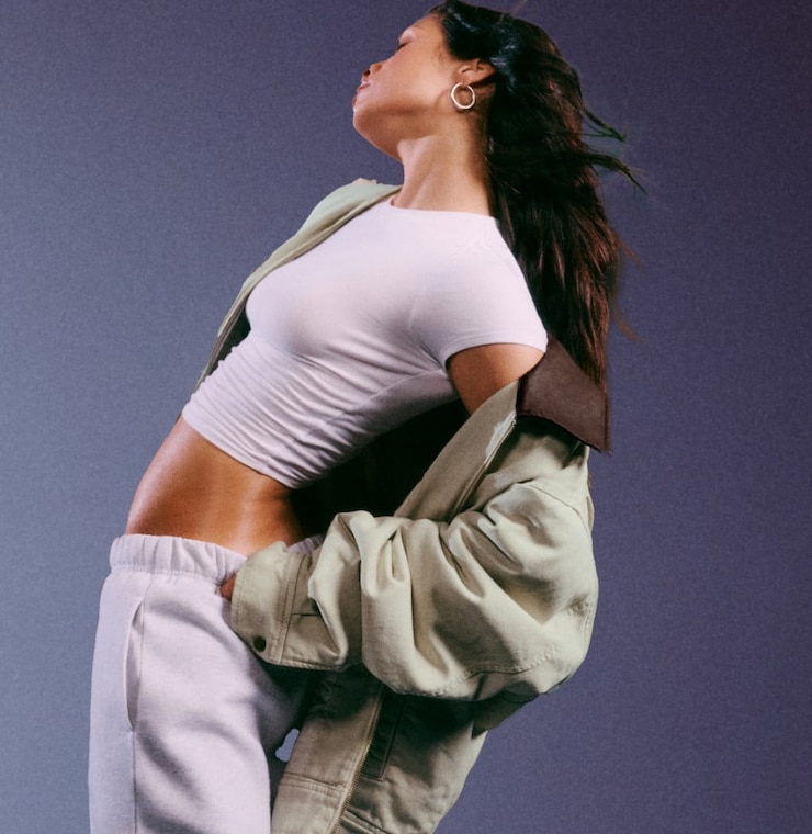 Model poses in a white t-shirt, worker jacket, and sweats.