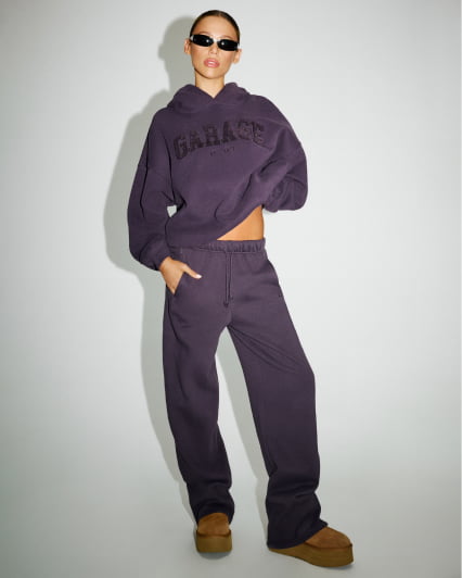 Hallie Batchelder walks down the street in a purple tank top and matching sweats.